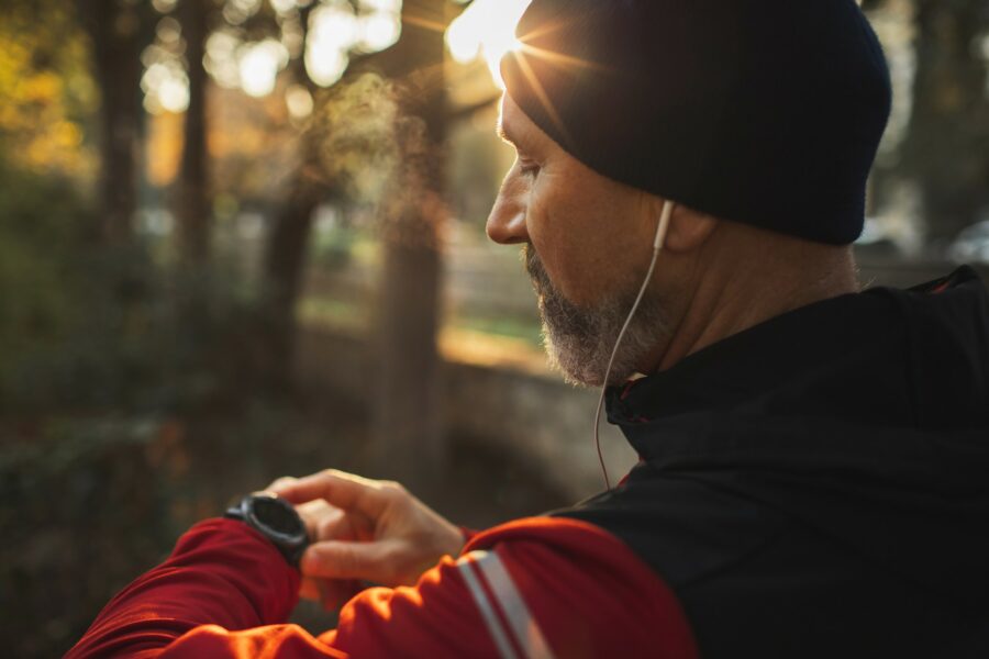 A man in a red jacket is checking data on a device on his wrist